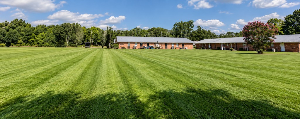 Professionally striped commercial lawn in front of brick buildings in southern Alabama